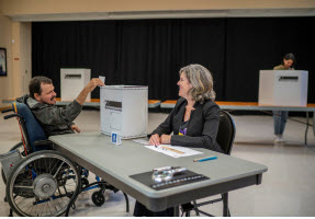 Électeur en fauteuil roulant en train de voter à un bureau de vote